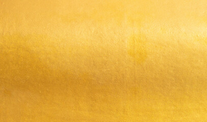 Gold wall texture background. Yellow shiny gold foil paint on wall surface with light reflection