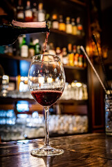 bartender pouring red wine into a glass in cafe or bar
