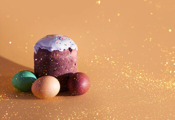 Colored Easter eggs and cake on a yellow background with a golden sheen. The background has space to copy. High quality photo