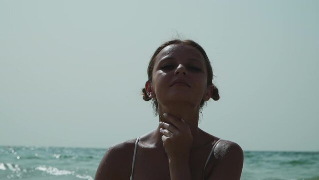 Beautiful caucasian girl with two ponytails in a bikini. A European woman with two bunches on the sides of her head is resting on the sea. Lely is sunbathing. The girl lies in the waves of the ocean.