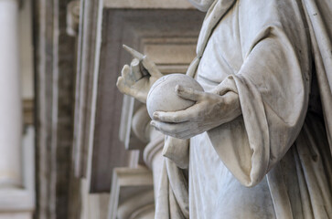 detail of a marble sculpture with a hand holding a sphere-world, geometric space. Monument in a...