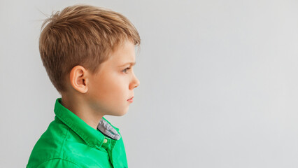Profile Portrait Of Blonde Preteen Boy Looking Aside, Gray Background