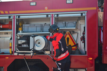 Fototapeta premium Firefighter taking tools from the fire truck to extinguish a fire