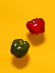 Red and green peppers levitation on yellow background