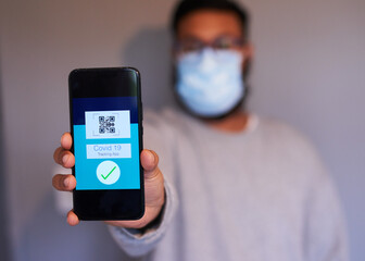 Covid19 tracking app held by a man wearing a surgical mask