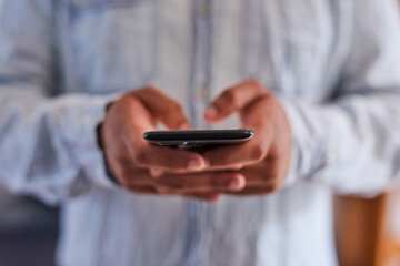 A tight shot of a man's hands typing on a mobile phone