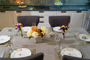 served dining table with utensils and flowers in the dining room. 