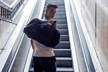 Young caucasian man moving up on an escalator at the airport.