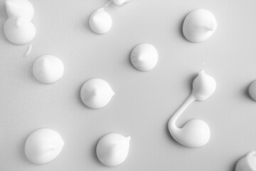 The texture of white cream on a gray background. Smear of skincare cosmetics product. Wellness and beauty concept