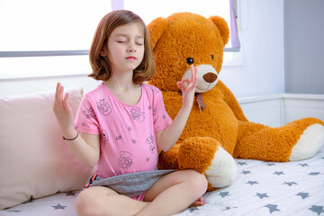 beautiful European girl practicing and relaxing with Mindfulness next to her stuffed animal at home she is happy
