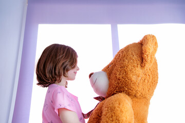 happy young girl playing with her big teddy
