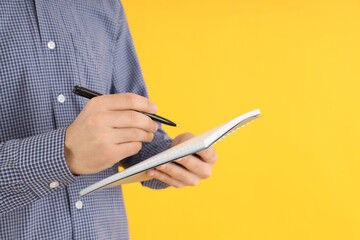 Guy with notebook and pen on yellow background