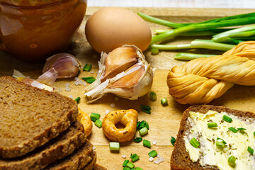 tasty lunch in rural style, healthy food - bread and butter sandwich, feta cheese, eggs, green leek and rye bread, cooked food on a white wooden boards