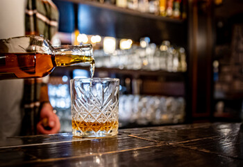 Barman pouring whiskey on glass in bar