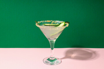 Jalapeno cocktail on pink table against green background
