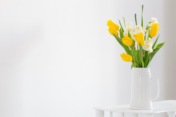 white and yellow spring flowers  in vase on white background