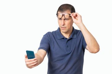 Mid adult wearing eyeglasses with eyesight problems trying to read phone text with white background - obrazy, fototapety, plakaty