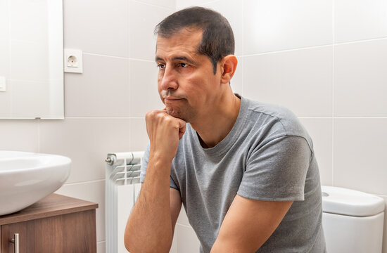 Shot of an bored and constipated man using the toilet at home