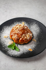 Cake with nuts, icing and powdered sugar, on a dark dish and on a light gray background