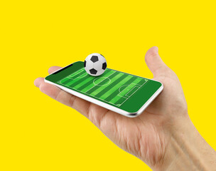 Cropped shot of a man using a smart phone as football field, watch online, bet online concept with...