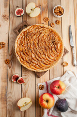 Cake with apples, nuts, on a wooden background, decorated with figs