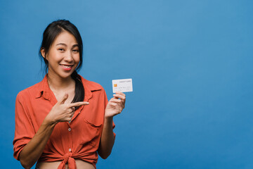 Young Asia lady show credit bank card with positive expression, smiles broadly, dressed in casual clothing feeling happiness and stand isolated on blue background. Facial expression concept.