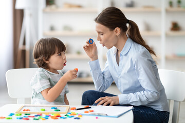 Female speech therapist curing child's problems and impediments. Little boy learning letter O with...