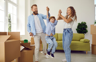 Fototapeta na wymiar Happy young Caucasian parents play with small child unpack on moving day to new home. Overjoyed family with kid celebrate relocation to own house. Bank loan or mortgage, rental, real estate.