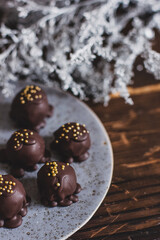 Dark chocolate handmade candy balls on handmade plate on dark wooden background with the cup of tea in a white cup