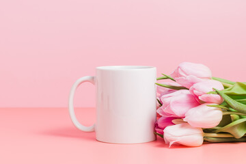 White mockup mug with pink tulips on pink background, cup for logo and design, spring holiday concept