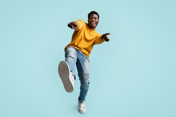 Carefree handsome black guy posing on blue, laughing and gesturing