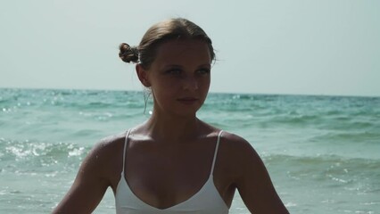 Beautiful caucasian girl with two ponytails in a bikini. A European woman with two bunches on the sides of her head is resting on the sea. Lely is sunbathing. The girl lies in the waves of the ocean.