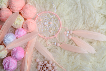 Handmade vintage dream catcher and small balls of yarn on soft white background