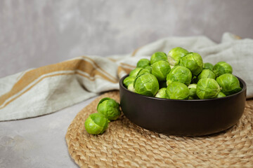 Black bowl with fresh Brussels cabbage on table, closeup