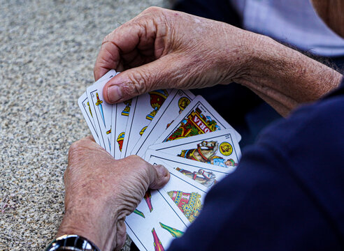 Persona mayor y jubilada jugando con una baraja de cartas espa&ntilde;olas