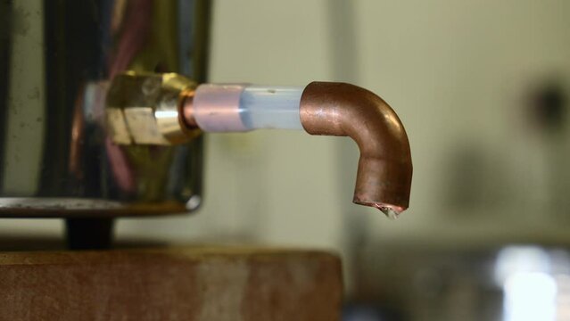 Alcohol is dripping out of a pipe while destilling process