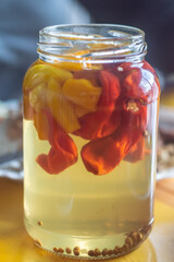Canned yellow peppers in a jar on wooden background,natural light