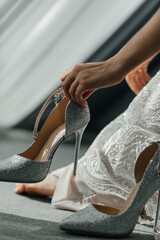 Shiny wedding shoes in the hands of the bride close-up