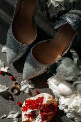Composition with shiny wedding shoes and rings, as well as with a pomegranate