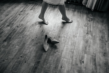 The bride walks on tiptoe past the wedding shoes lying on the floor