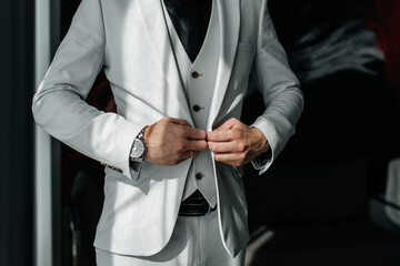 The groom puts on a jacket and vest before the wedding