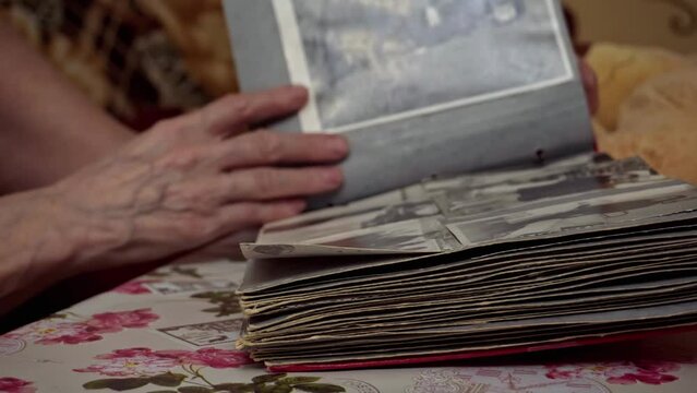 An adult on a table flips through a photo album with old photos. Anastalgia, memories, captured moments. Photo in photo album. Soft selective selective focus