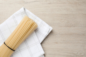 Uncooked rice noodles with napkin on wooden table, top view. Space for text