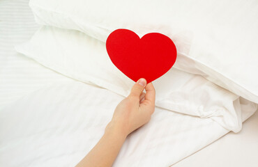 Paper red hearts on a white pillow. A surprise in the bedroom for loved ones.