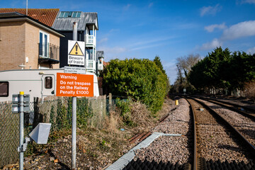 Warning signs on a level crossing informing the public to beware of trains and that trespassing on the tracks will lead to prosecution and a fine to pay - obrazy, fototapety, plakaty