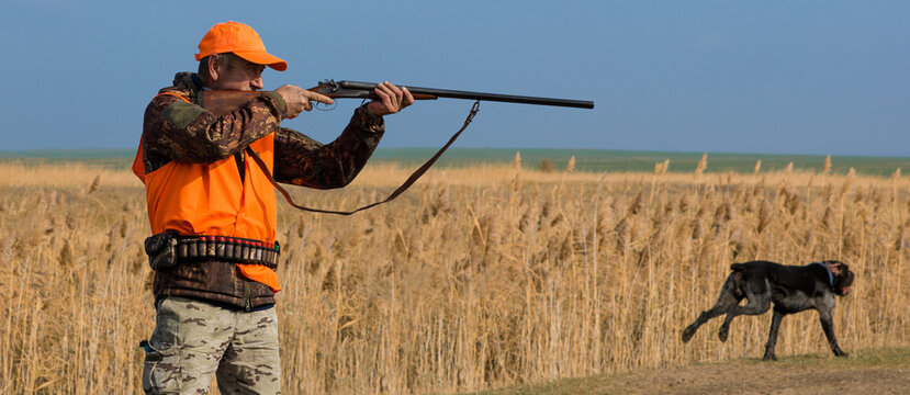 Hunter man in camouflage with a gun during the hunt in search of wild birds or game. Autumn hunting season.