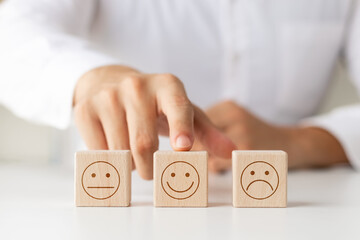 Customer satisfaction survey concept, customer's hand selects wooden cube with smile face icon, best service excellence rating for satisfaction.