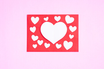 Red envelope with heart papercut on pink background