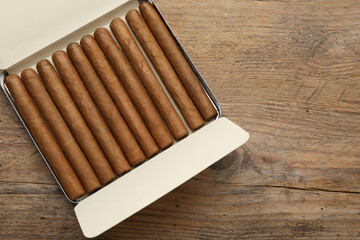 Humidor with cigars on wooden table, top view. Space for text
