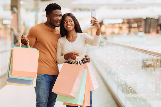 Happy black couple taking selfie at shopping mall